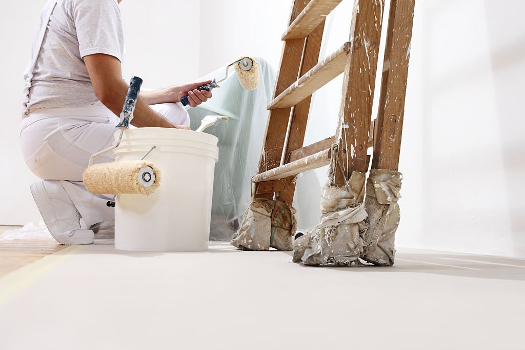 painter man at work with a roller, bucket and ladder, bottom view